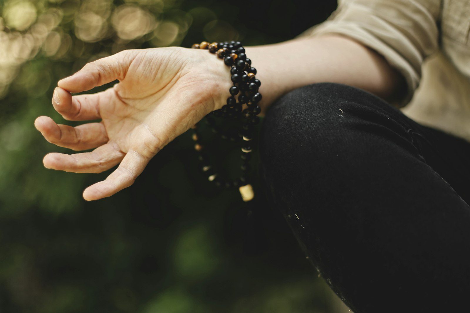 Mains posées, mala de méditation au poignet
